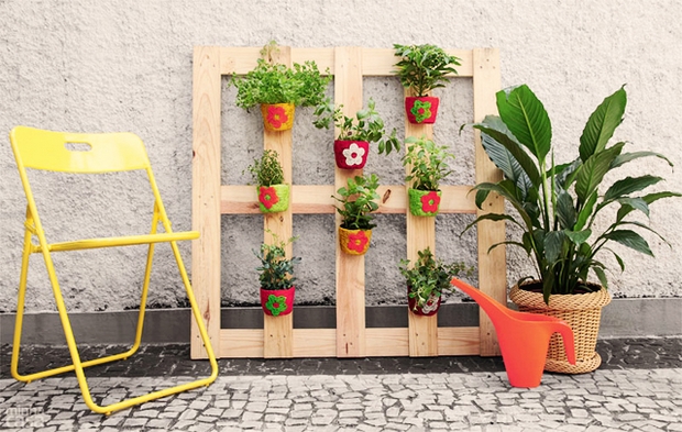 Vertical pallet garden decorated flower pots white wall yellow chair paver